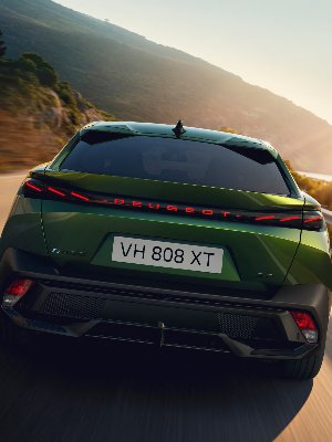 Green Peugeot E-408 car rear view on a road, showing licence plate VH 808 XT.