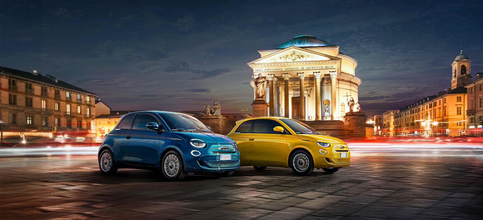 Blue and yellow cars parked in front of a neoclassical building at night.