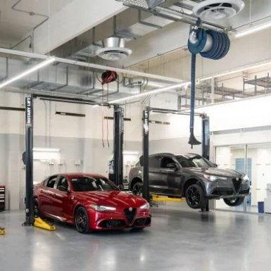 Two cars on lifts in a modern car service workshop.