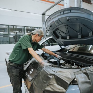 Mechanic inspecting engine under open car bonnet in a garage.