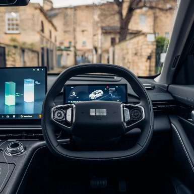 Steering wheel and dashboard of a modern car with digital displays showing stats.