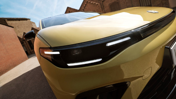 Close-up of a yellow car's front end with sleek headlights and a badge on the bonnet.