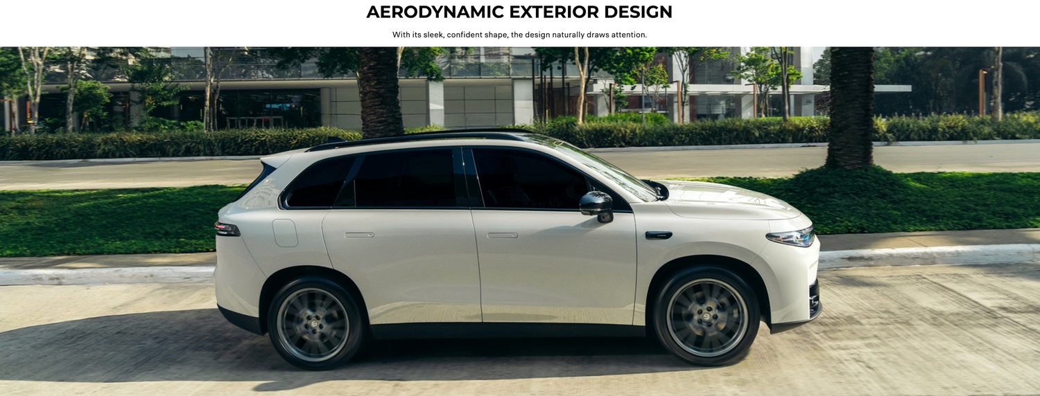 Side view of a white SUV driving on a road in an urban setting.