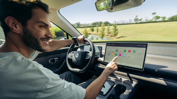 Man using touchscreen in a car with a view of a park through the window.