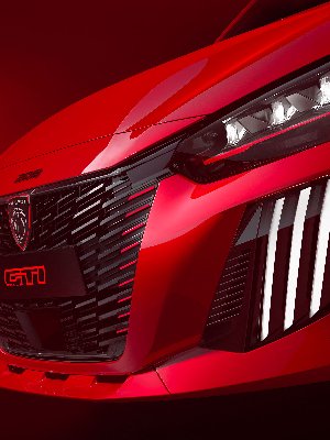 Close-up of a red Peugeot 208 GTI car front with LED headlights and logo.