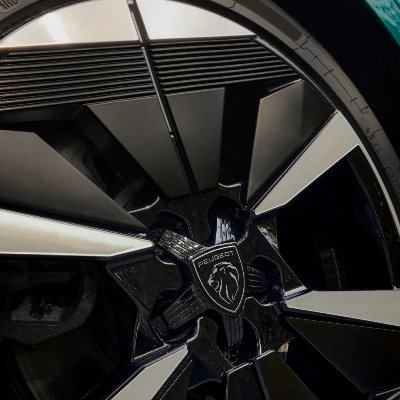 Close-up of a Peugeot car alloy wheel with lion emblem.