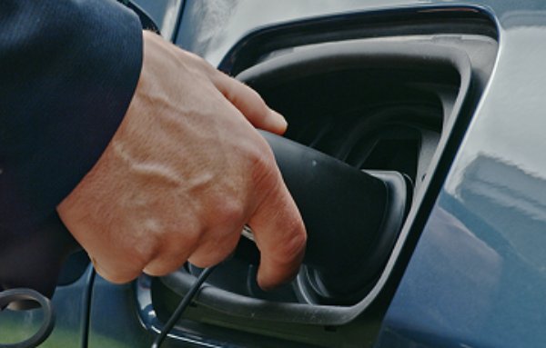 Hand plugging in an electric vehicle charger.