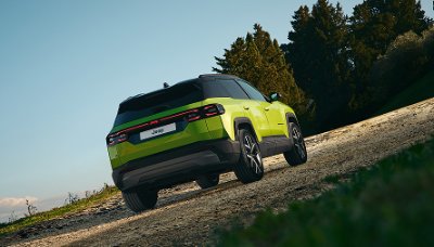 Green SUV viewed from behind on a gravel surface.