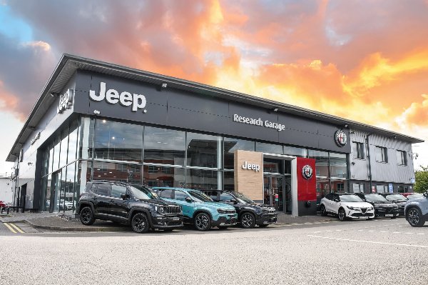 Jeep and Alfa Romeo dealership exterior with cars parked outside.