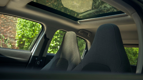 Interior view of a car's sunroof and grey front seats.
