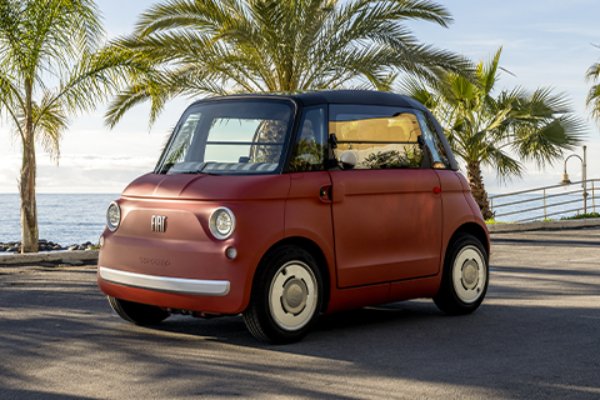 A compact red Fiat 500 Topolino parked near palm trees.